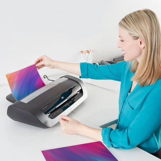 GBC Fusion 6000L on a desk while a user feeds a laminated sheet