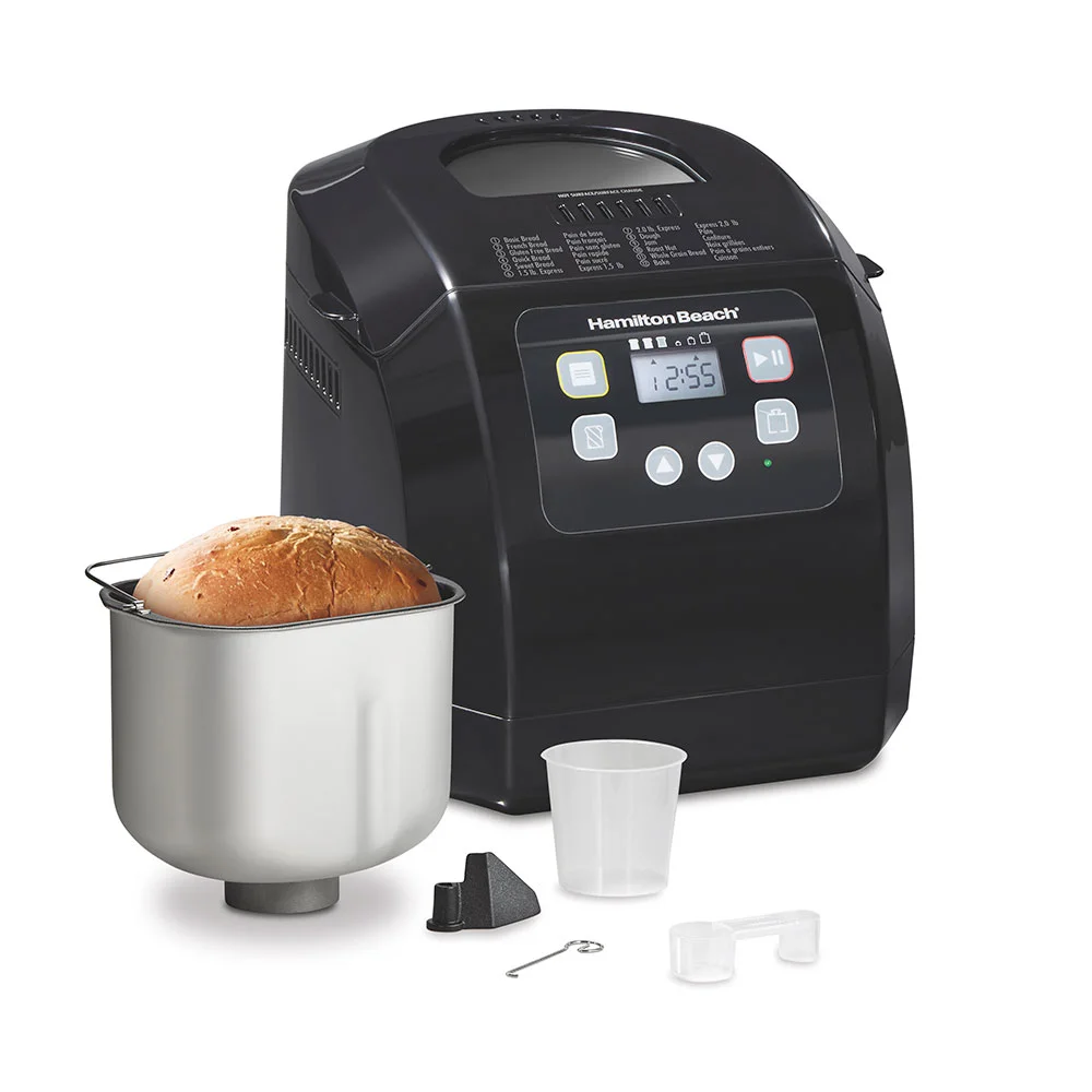 Black Hamilton Beach 29982 bread machine beside its loaf pan, measuring accessories and kneading paddle