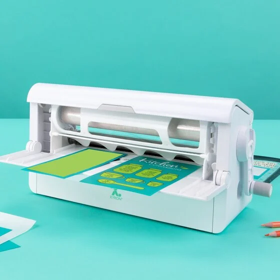 Xyron Creative Station with its lid open and craft material in the feed tray